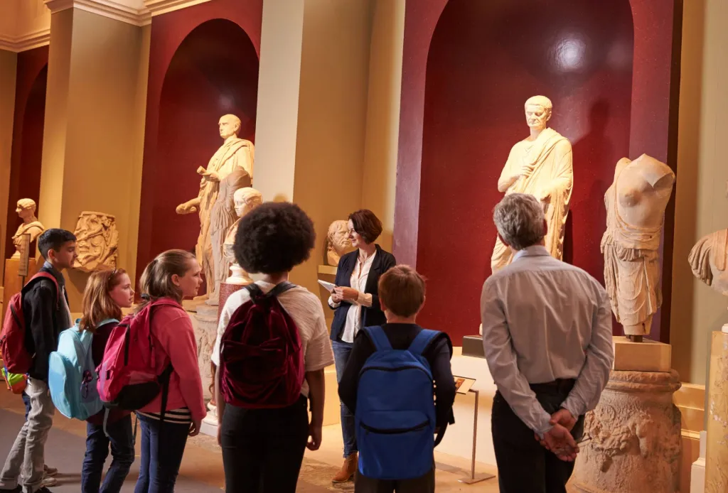 Group of children and adults studying an interactive map display in a museum exhibit.