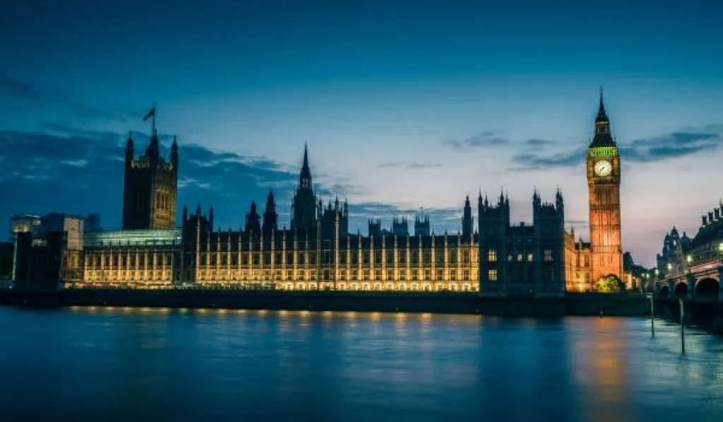 Houses of Parliament and Big Ben illuminated at dusk, reflected in the River Thames