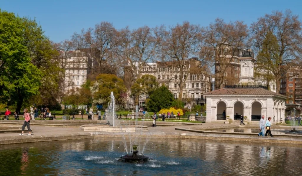 People walking by the Italian Gardens fountain in London’s Hyde Park on a sunny day.