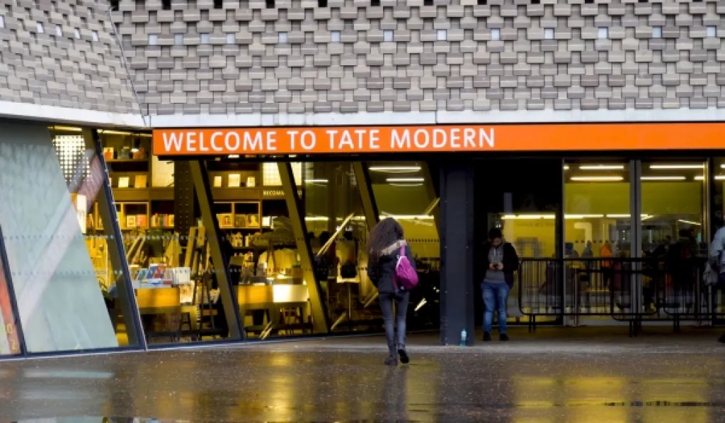 Entrance to Tate Modern art museum in London with visitors outside on a rainy day.