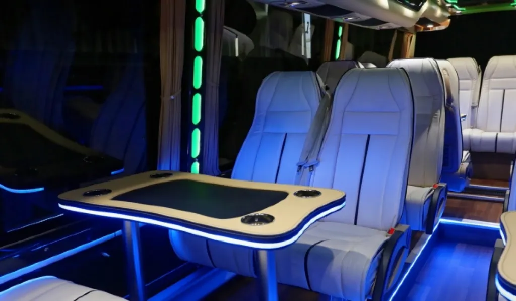 Luxury coach interior with LED lighting, leather seats, and a built-in table with cup holders.