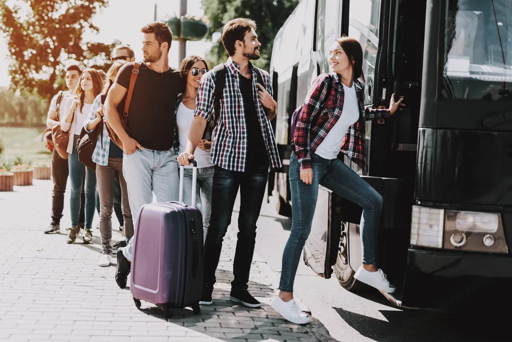 Group of young adults boarding a coach with luggage for a group travel trip.