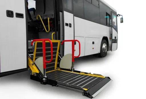 Coach bus with extended wheelchair lift and red safety rails on white background.